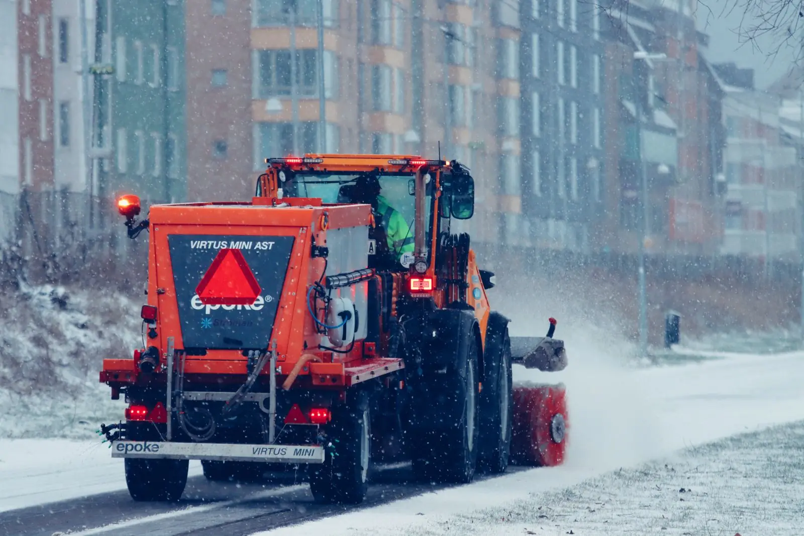 Räumfahrzeug mit Streuer in einer verschneiten Wohnstraße